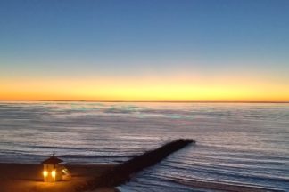 photo: a lifeguard tower with lights on, at sunset on a beach in Southern California