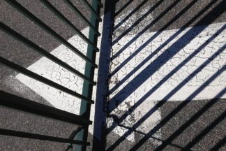 photo: driveway pavement painted with a large white arrow that goes under a closed metal gate