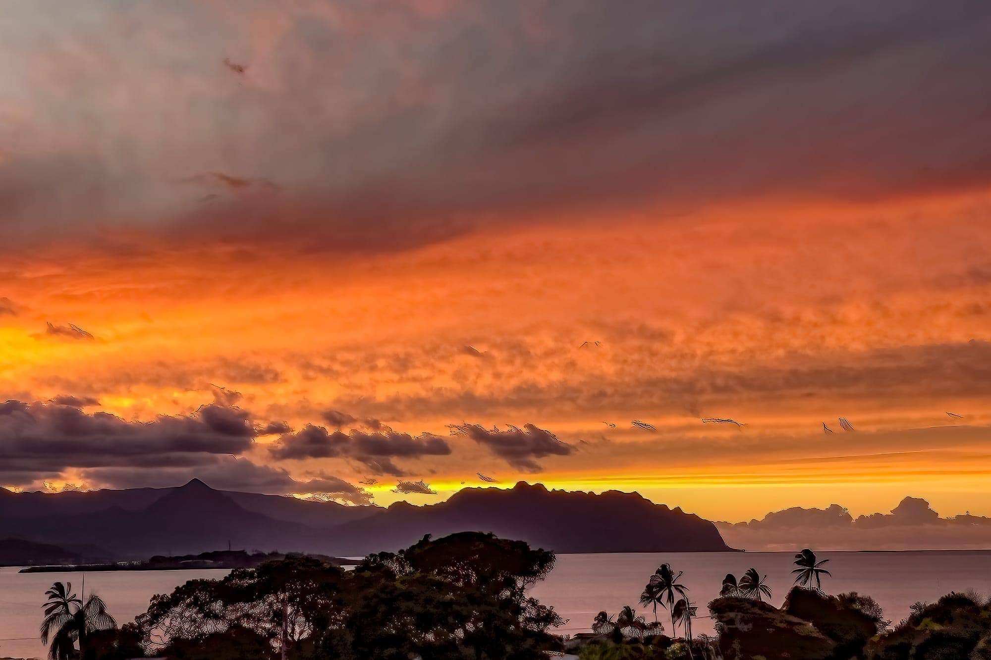 photo: colorful sunset over Coconut Island in Kaneohe Bay, Oahu, with backdrop of the Ko'olau mountains.
