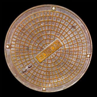 photo: manhole cover with single word 'EDISON' - black background